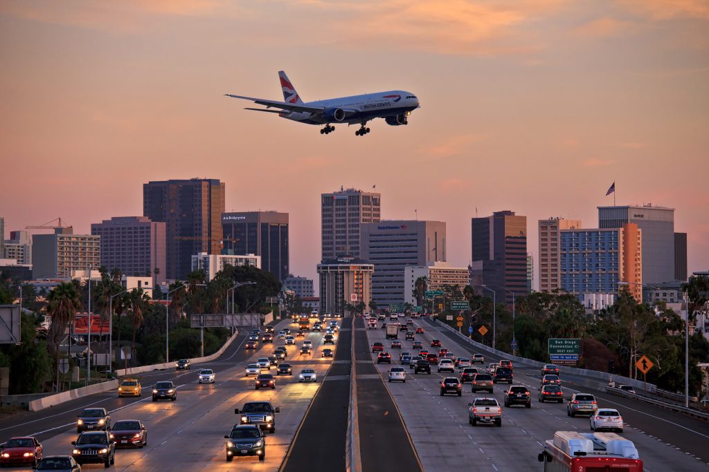 Jet aircraft on landing approach flying low over city freeway